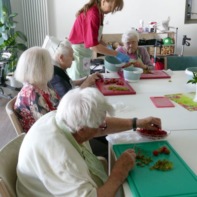 Bewohner:innen des Rudolf-Walter-Hauses schneiden Erdbeeren